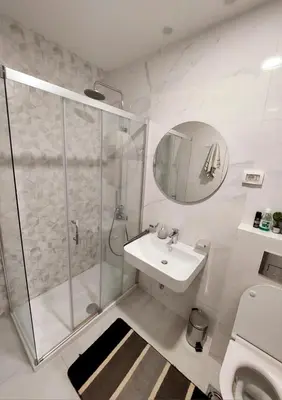 a white bathroom with a shower and a sink at New York - Central Point in Podgorica