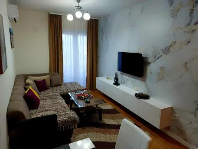 a living room with a couch and a tv on a wall at New York - Central Point in Podgorica