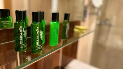a row of green shampoo bottles on a shelf in a bathroom at Villa Allende in Budva
