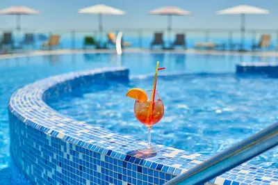 a drink with an orange slice in a swimming pool at Villa Allende in Budva