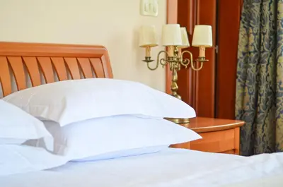 a bed with white pillows and a table with two lamps at Villa Allende in Budva