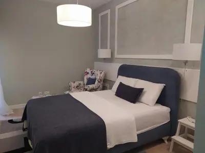 a bedroom with a bed with a blue headboard and two chairs at Soho City Apartment with Garage in Bar