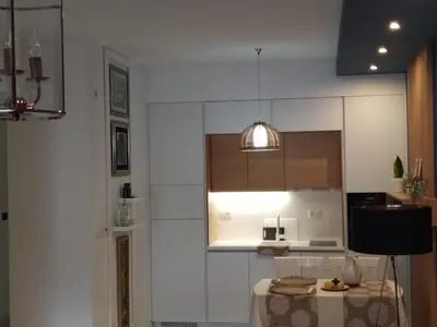 a white kitchen with a table and a light at Soho City Apartment with Garage in Bar