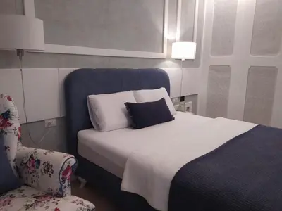 a bed with a blue headboard and a chair in a room at Soho City Apartment with Garage in Bar