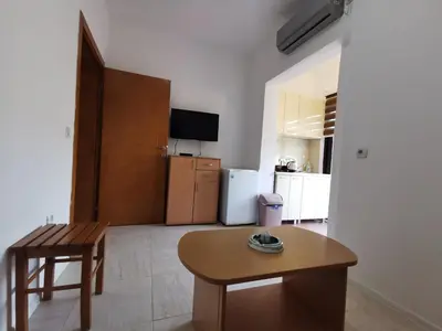 a living room with a table and a refrigerator at Apartments Val Maslina in Utjeha