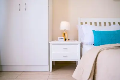 a bedroom with a bed with a white nightstand and a lamp at Apartments Lungo Mare Ulcinj in Ulcinj