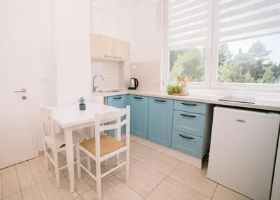 a kitchen with blue cabinets and a white table at Apartments Lungo Mare Ulcinj in Ulcinj