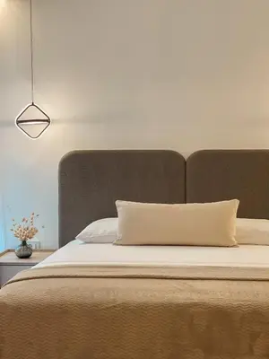 a bed with a tan headboard and a white pillow at Casa Nita in Ulcinj