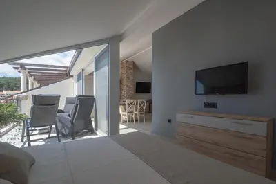 a bedroom with a television and a balcony with chairs at SYMPHONY in Petrovac na Moru