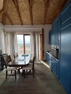 a kitchen with a table and chairs and a kitchen with blue cabinets at Apartments Teona in Bar