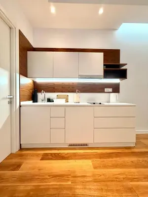 a kitchen with white cabinets and a wooden floor at Condo Studio Plaza in Budva