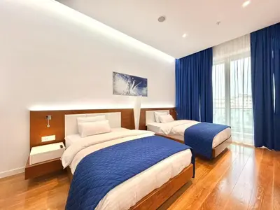 two beds in a hotel room with blue curtains at Condo Studio Plaza in Budva