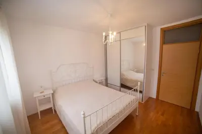 a white bedroom with a bed and a mirror at Apartment Plamenatz in Bar