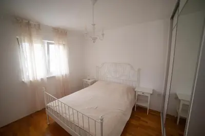 a white bedroom with a bed and a window at Apartment Plamenatz in Bar