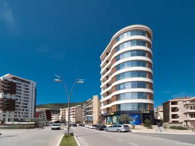 a tall building with cars parked in front of a street at Seaside Rest Apartments in Budva