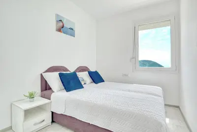 a white bedroom with a bed and a window at Two Bedroom House with Sea View MAJ in Ðurovići