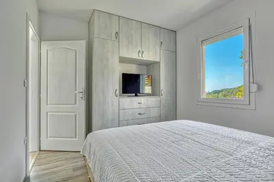 a white bedroom with a bed and a window at Two Bedroom House with Sea View MAJ in Ðurovići