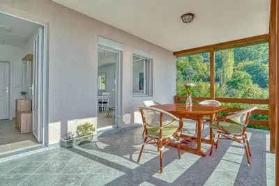 a dining room with a wooden table and chairs at Two Bedroom House with Sea View MAJ in Ðurovići