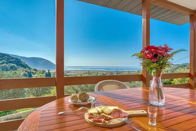 a wooden table with a plate of food and flowers on it at Two Bedroom House with Sea View MAJ in Ðurovići