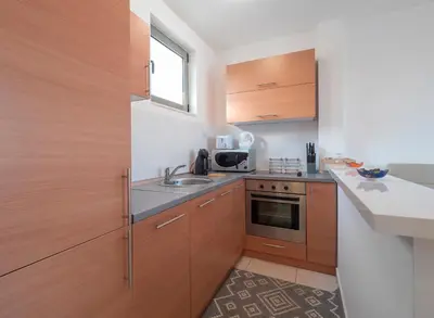 a small kitchen with wooden cabinets and a sink at Sea view Two bedroom Family Apartment with pool - Sunset Ivanovići in Becici
