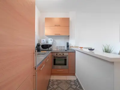 a small kitchen with wooden cabinets and a sink at Sea view Two bedroom Family Apartment with pool - Sunset Ivanovići in Becici