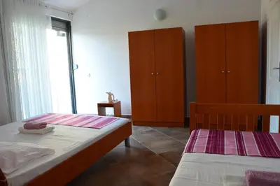 a bedroom with two beds and wooden cabinets at NEXT DOOR HOUSE in Ulcinj