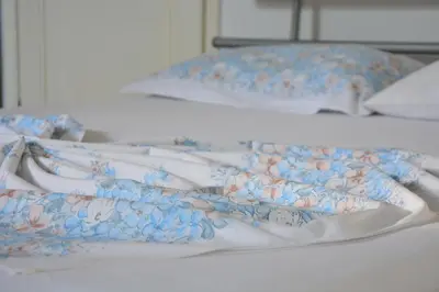 a white bed with a floral blanket and pillows at NEXT DOOR HOUSE in Ulcinj