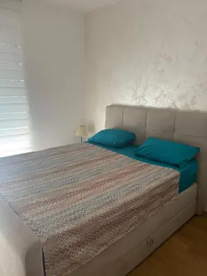 a bed with two blue pillows in a bedroom at Anja Lux Apartman in Budva