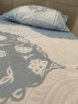 a bed with a blue and white blanket and a pillow at Anja Lux Apartman in Budva