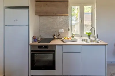 a kitchen with white cabinets and a sink at AparDibra in Bar