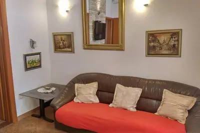 a leather couch with a red cushion in a living room at Garden Apartment- near sea 2 in Dobrota