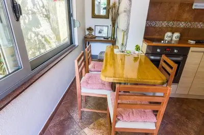 a kitchen with a wooden table and chairs in a room at Garden Apartment- near sea 2 in Dobrota