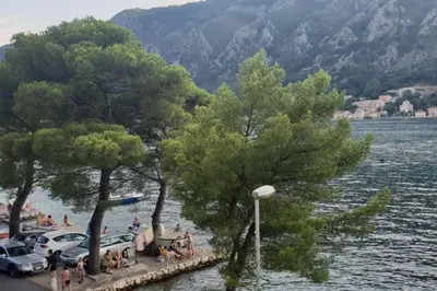 a group of people sitting on a dock next to a lake at Garden Apartment- near sea 2 in Dobrota