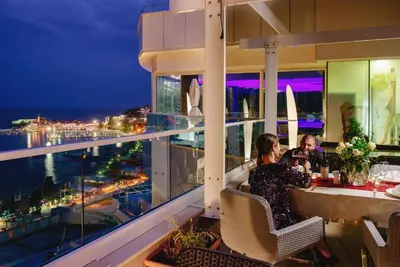 a couple sitting at a table on a balcony at night at Apartment in the luxury hotel near beach in Budva