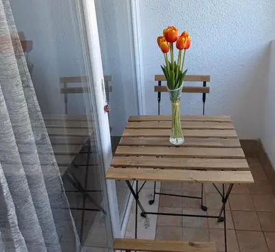 a vase of orange tulips sitting on a wooden table at Podgorica Great location in Podgorica