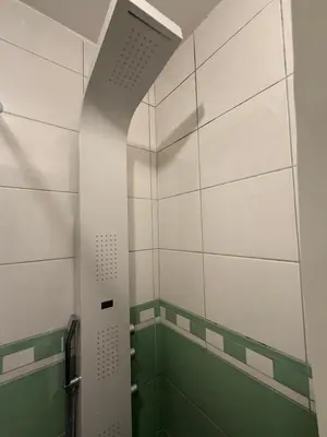 a bathroom with a shower with green and white tiles at Podgorica Great location in Podgorica