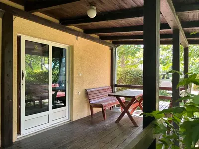 a wooden porch with a bench and a table at Christopher's apartments in Ulcinj