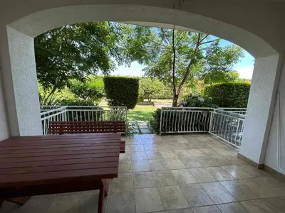 a porch with a wooden bench and a fence at Christopher's apartments in Ulcinj