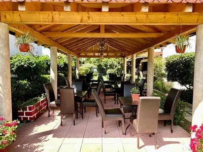 a patio with tables and chairs under a wooden pergola at Christopher's apartments in Ulcinj