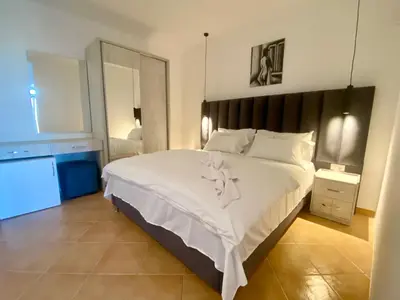 a bedroom with a large bed with white sheets at Christopher's apartments in Ulcinj