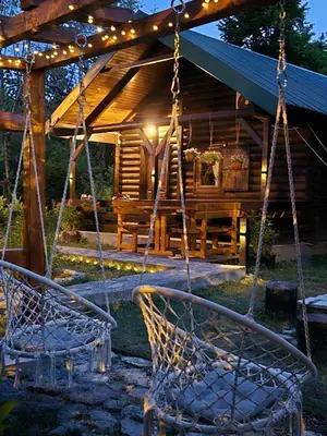 two swings in front of a log cabin at night at Cabin House Dubovik in Cetinje