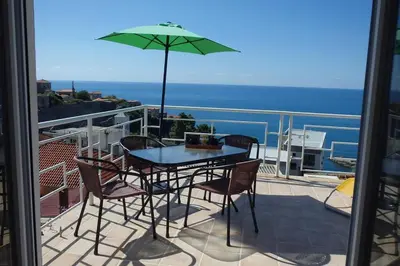 a table and chairs on a balcony with an umbrella at Apartman Aleksandra in Ulcinj