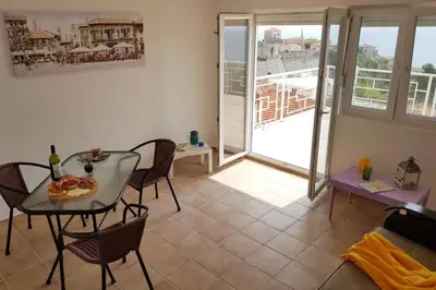 a living room with a table and chairs and a balcony at Apartman Aleksandra in Ulcinj