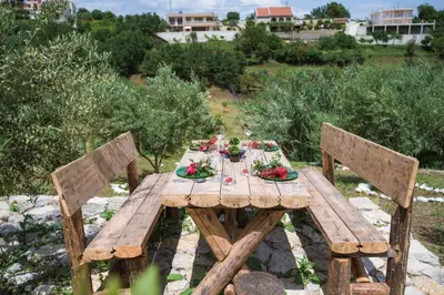 a wooden table with two wooden chairs and a table with flowers at Madre Natura Glamping in Ulcinj