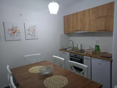 a kitchen with a wooden table and a table and chairs at Apartman Nikocevic 2 in Bar