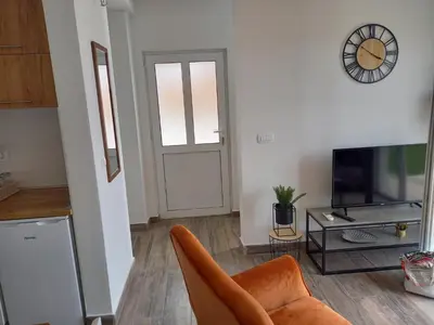 a living room with a couch and a television and a clock at Apartman Nikocevic 2 in Bar