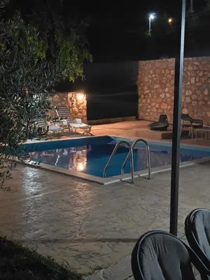 a swimming pool at night with chairs around it at Apartman Nikocevic 2 in Bar