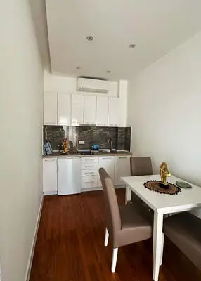 a white kitchen with a white table and chairs at Arte Luxury Pool Apartmets in Ulcinj