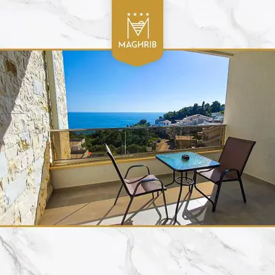 a table and chairs on a balcony with a view of the ocean at Maghrib Hotel in Ulcinj
