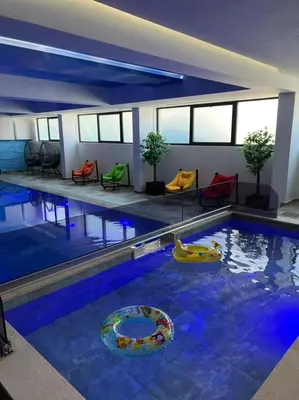 a large swimming pool with colorful chairs in a building at Maghrib Hotel in Ulcinj